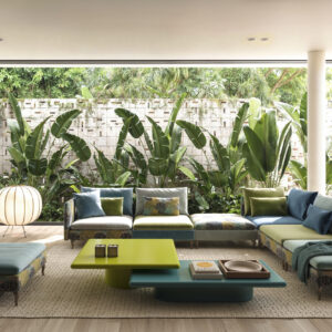 Spacious living room featuring large glass windows that offer a stunning view of lush tropical plants and garden outside, creating a bright and airy atmosphere.