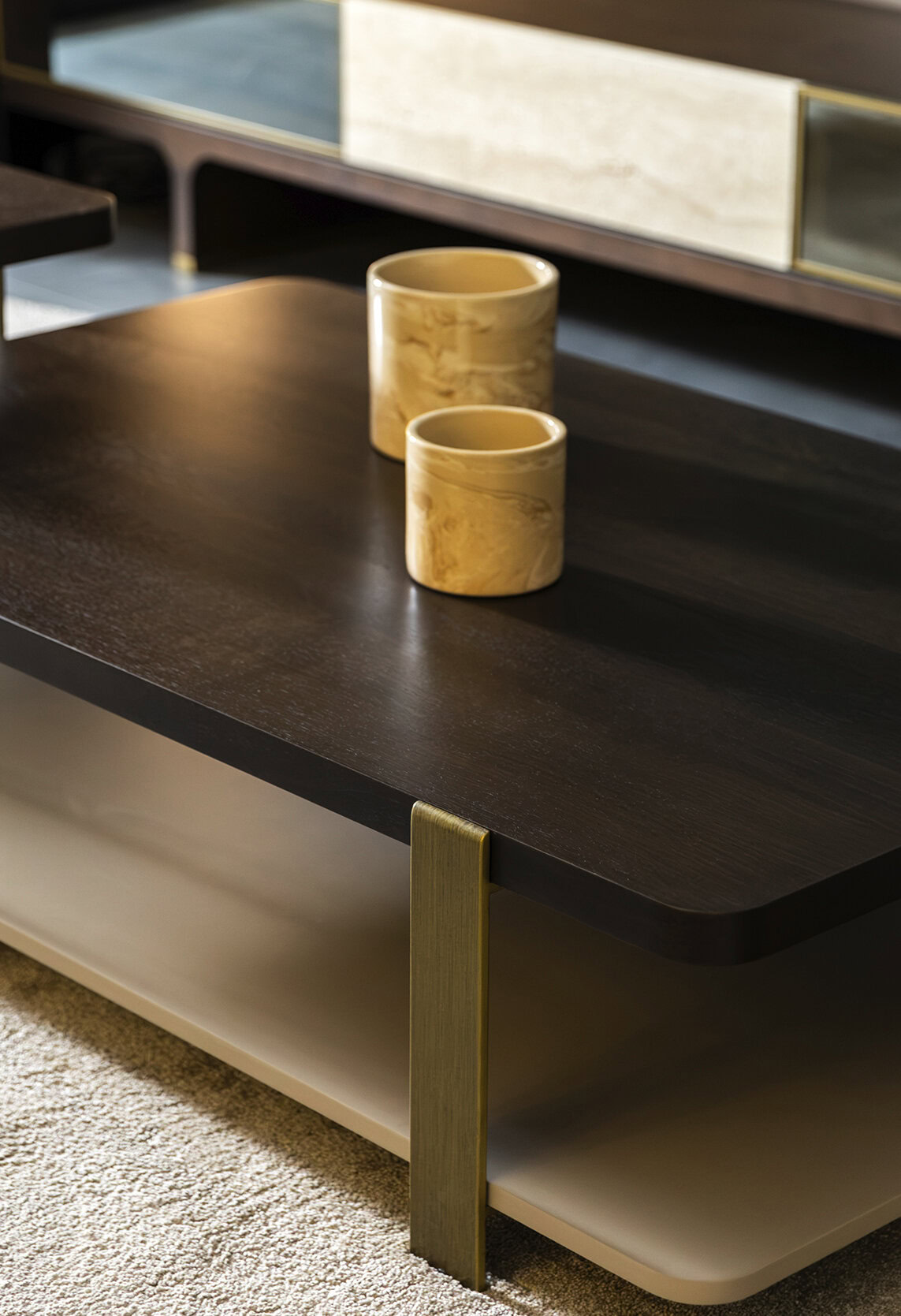 Elegant modern coffee table by Saloni Furniture with a dark wood finish and gold accents, featuring two beige marble vases on top.