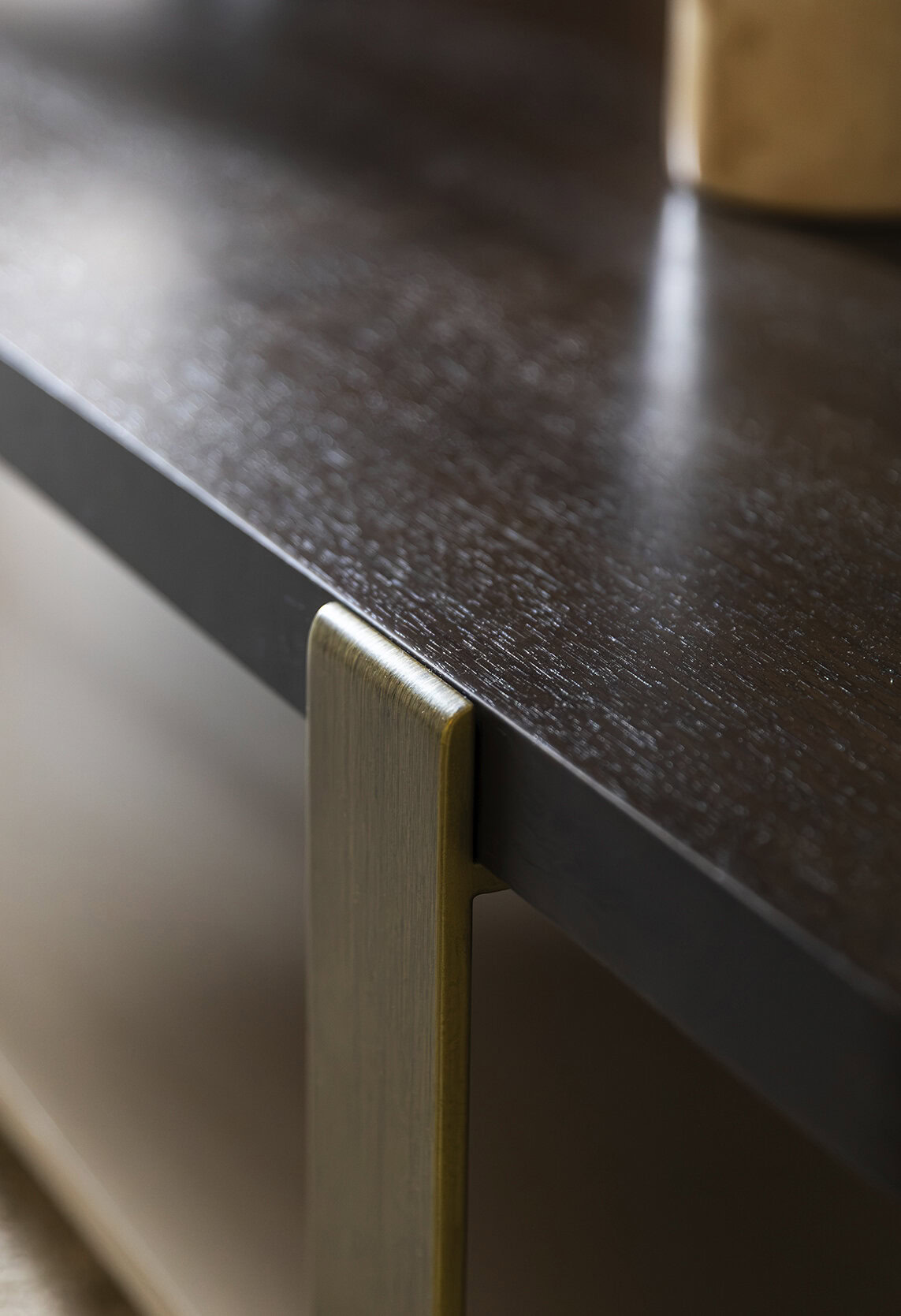 Close-up of a dark wood table from Saloni Furniture showcasing smooth finish and elegant design details.