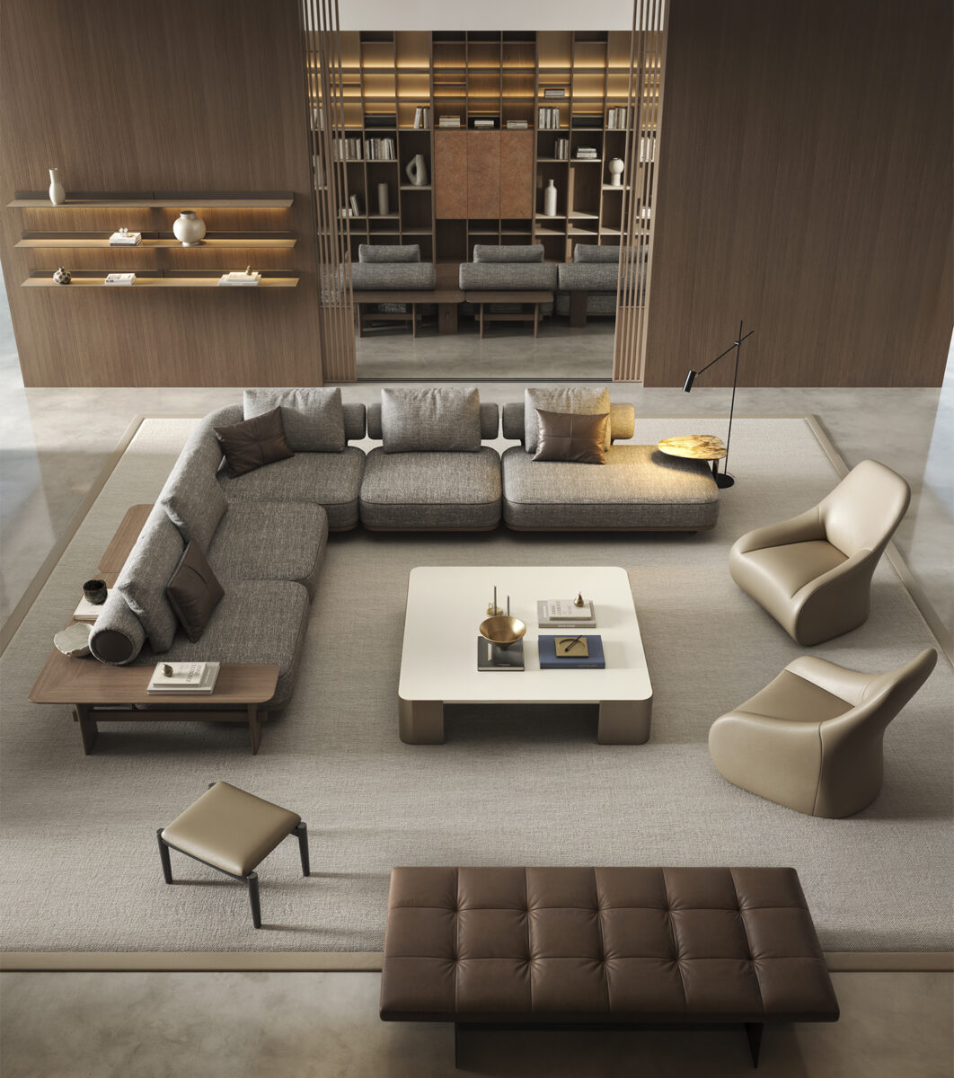 A contemporary living room featuring a large L-shaped gray sofa, two beige armchairs, a white coffee table, and a brown tufted ottoman, all set on a neutral area rug.
