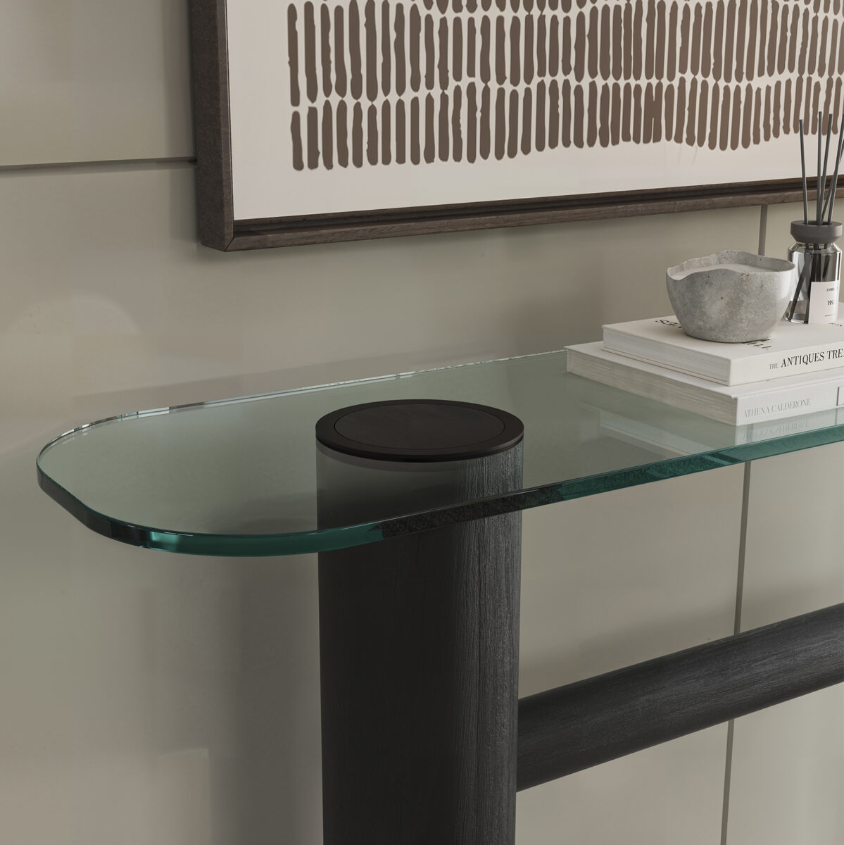 Elegant glass console table with black cylindrical base in contemporary interior design setting.