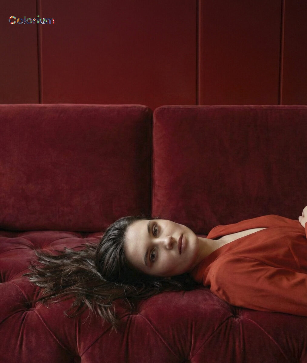 Elegant red velvet sofa from Saloni Furniture with a woman relaxing on it, showcasing luxurious home furniture design.