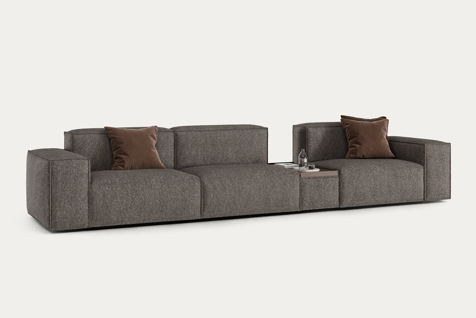 Contemporary grey sectional sofa with brown accent pillows, perfect for modern living rooms, from Saloni Furniture.