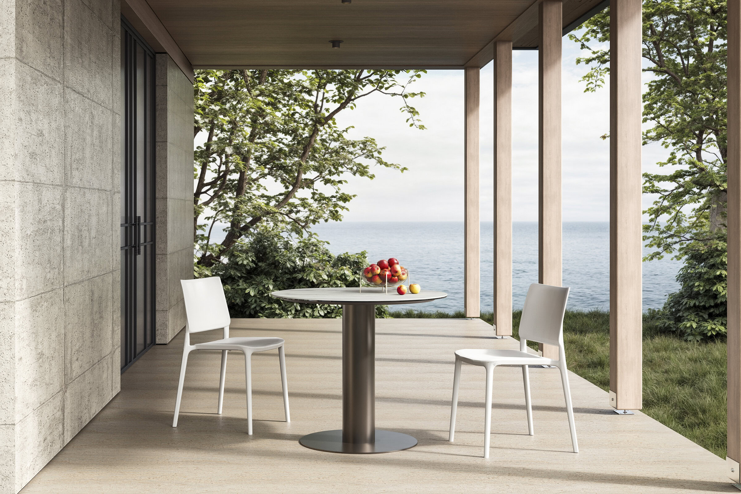Sleek modern white dining chairs and round table on a balcony overlooking the ocean with greenery, showcasing contemporary furniture design for outdoor spaces and coastal living.