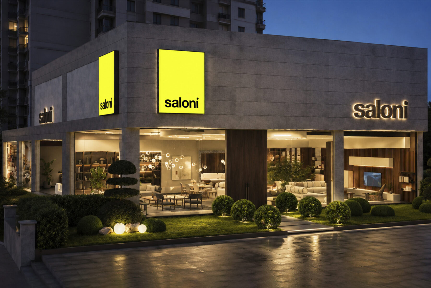Exterior view of Saloni Furniture store at night showcasing modern furniture displays and illuminated signage.