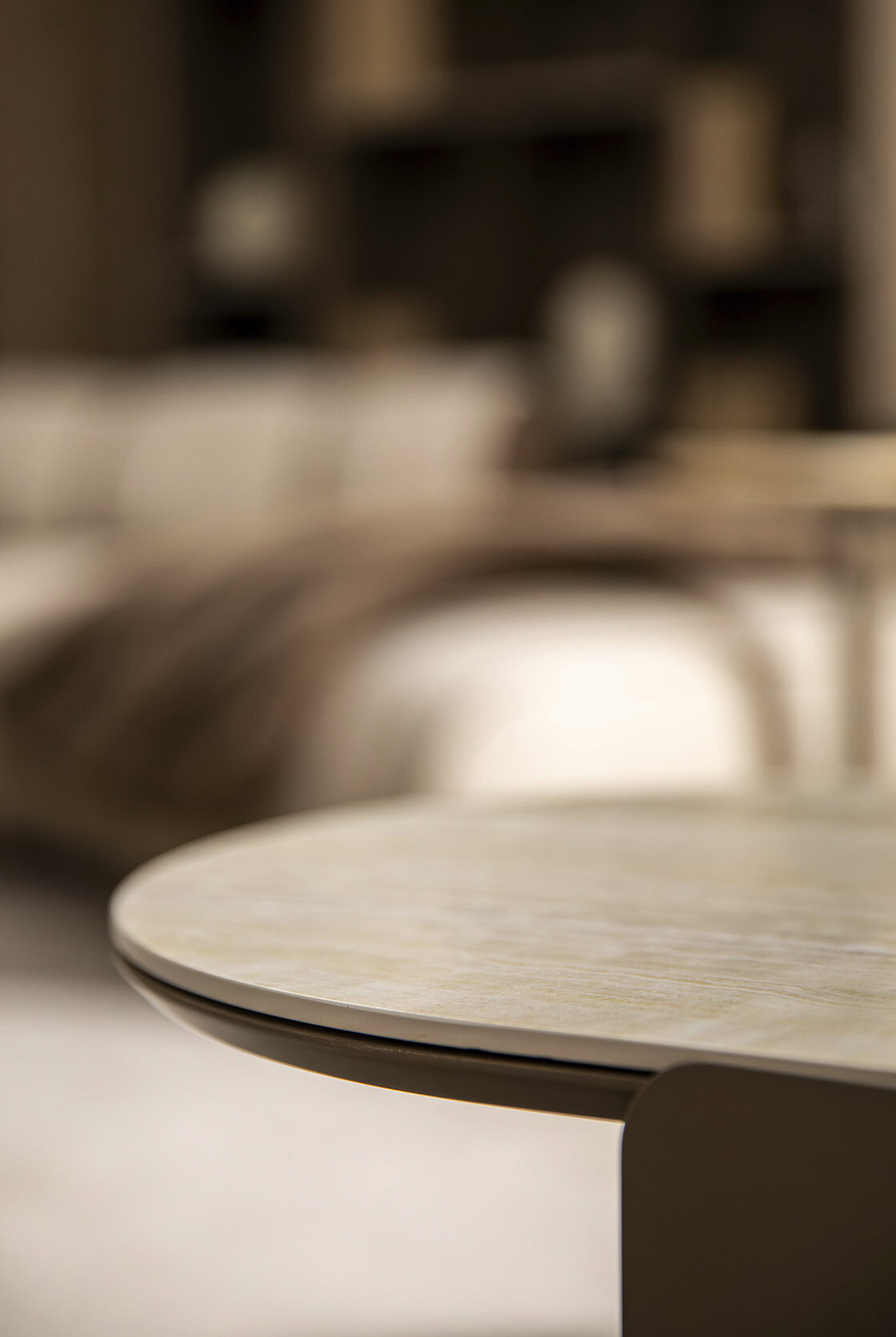 Close-up of a round wooden coffee table in a stylish modern living room with blurred background furniture and decor.