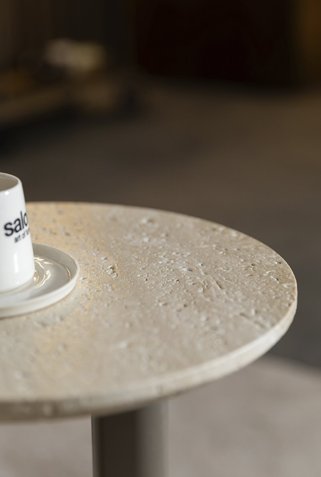 Close-up of a textured beige coffee table with a white mug on top, showcasing modern furniture design.